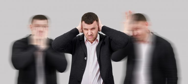 Homme exprimant de la frustration entouré de silhouettes floues - charge mentale et épuisement du DSI